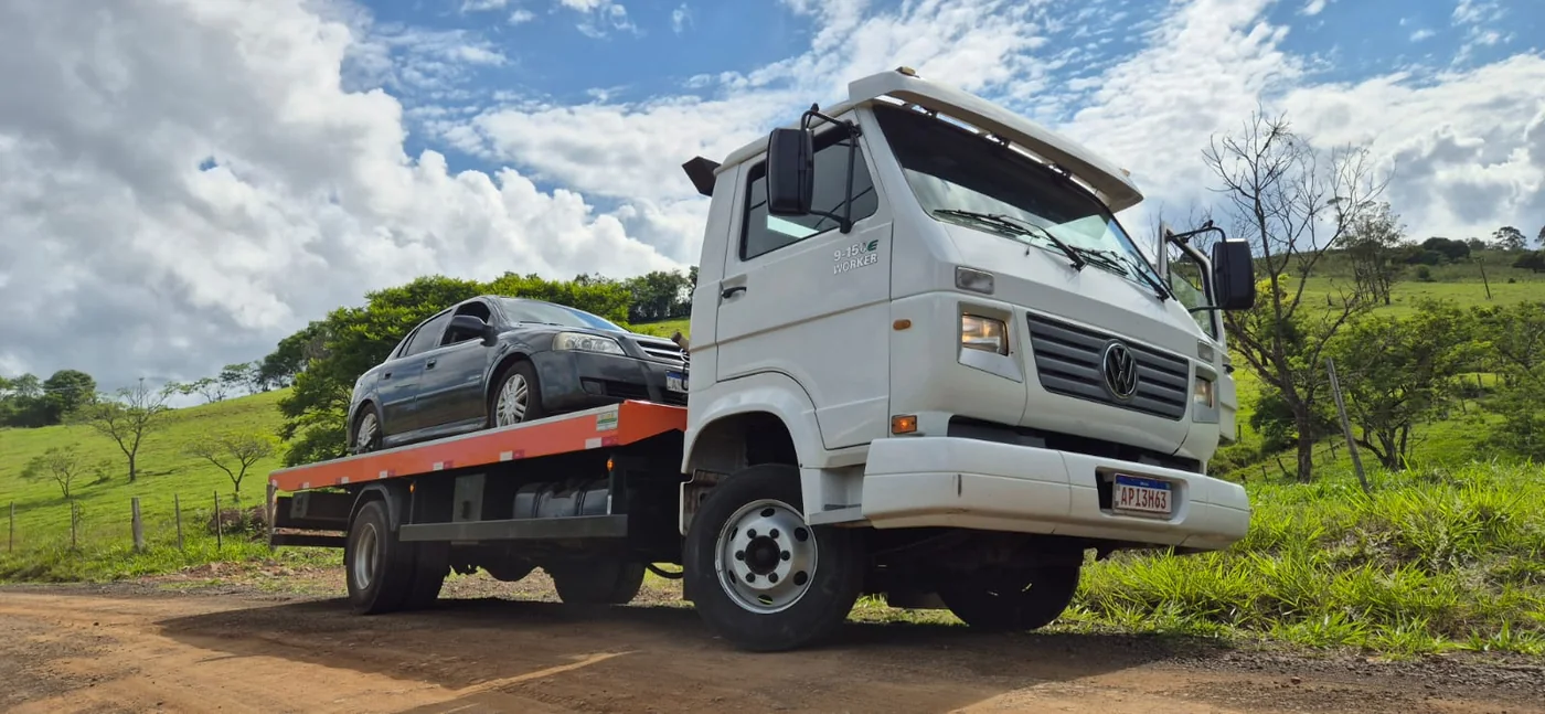 Caminhão-prancha real transportando carro em área rural